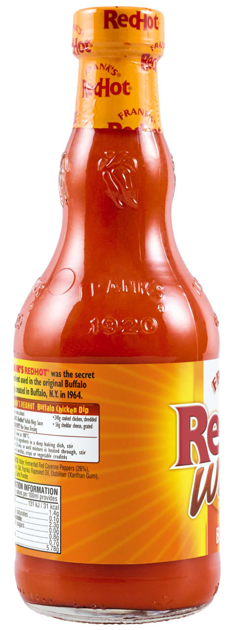A side view of a glass bottle of Franks Rdhot Bws Gb 24/148 Ml, showing the nutritional information, ingredients, and a recipe for Buffalo Chicken Dip on the yellow and orange label.