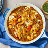 A vibrant shrimp curry prepared in a blue skillet with a rich sauce seasoned by Schwartz Medium Curry Powder 90G.