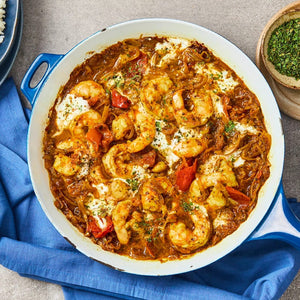 A vibrant shrimp curry prepared in a blue skillet with a rich sauce seasoned by Schwartz Medium Curry Powder 90G.