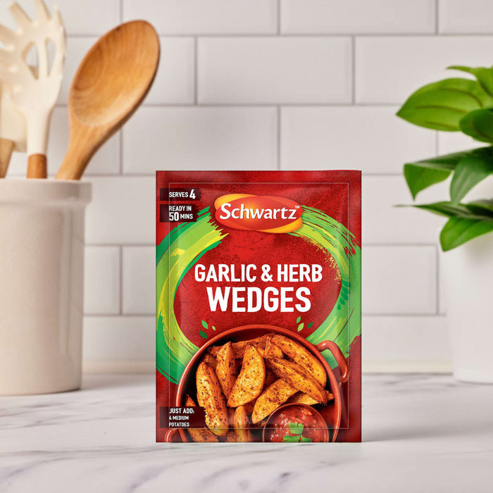 A packet of Schwartz Garlic And Herb Wedges, 38G is displayed on a marble countertop in a bright kitchen setting, ready to be used for cooking.