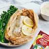A serving suggestion shows fish cooked in parchment paper with broccolini, all drizzled with a creamy sauce made from a packet of Schwartz Creamy Parsley Sauce 26G, which is visible in the corner.
