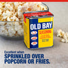 A tin of Old Bay Seasoning sits next to a bowl of popcorn to show it is excellent when sprinkled over popcorn or fries.