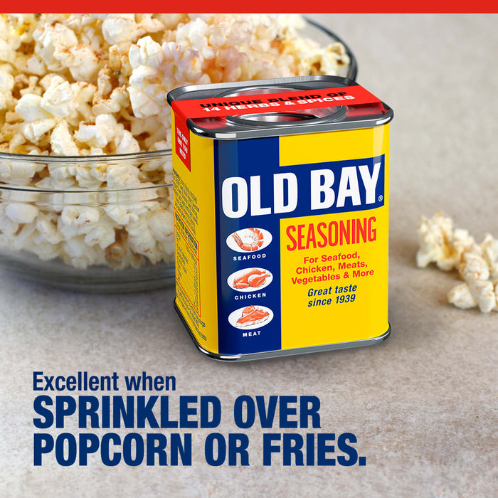 A tin of Old Bay Seasoning sits next to a bowl of popcorn to show it is excellent when sprinkled over popcorn or fries.