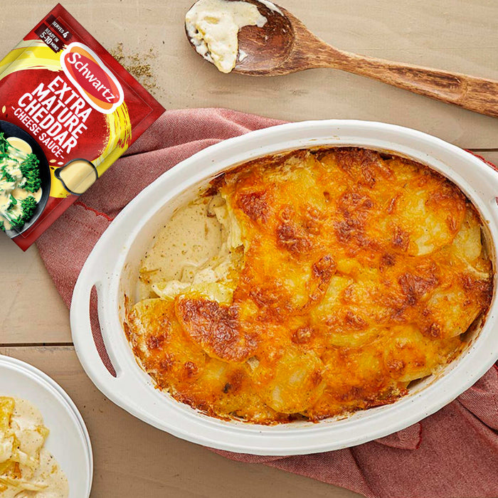 A freshly baked potato gratin in a white oval dish is shown next to a packet of Schwartz Extra Mature Cheddar Cheese Sauce 30G, suggesting the sauce was used to create the cheesy, golden-brown dish.
