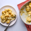 A delicious cauliflower cheese dish made with Schwartz Extra Mature Cheddar Cheese Sauce 30G is served on a plate next to the baking dish.