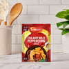 A packet of Schwartz Creamy Mild Peppercorn Sauce Mix 25G sits on a kitchen countertop, ready to be used for a quick meal.