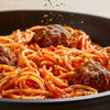 Dried herbs from the Spice Rack Engraved Gift Set are sprinkled over a steaming bowl of spaghetti and meatballs in a rich tomato sauce.
