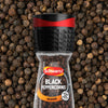 A Schwartz Black Peppercorns Adjustable Medium Grinder 35G is centered against a background of whole dried black peppercorns.