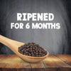 A wooden spoon filled with the high quality whole berries used in Schwartz Black Peppercorns Adjustable Medium Grinder 35G is shown against a dark background with text stating they are ripened for 6 months