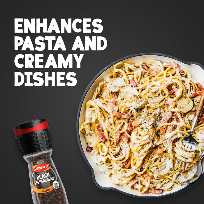 A bottle of Schwartz Black Peppercorns Adjustable Medium Grinder 35G is displayed next to a skillet of creamy pasta with bacon and mushrooms to show how it enhances pasta and creamy dishes.