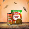 A jar of Schwartz Cumin Ground 37G and its corresponding refill pack sit on a rustic wooden table, with whole cumin seeds floating in the warm-toned background.