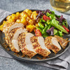 A plate of sliced chicken breast and roasted potatoes, seasoned with Schwartz Onion Granules 30G, is served with a fresh side salad.