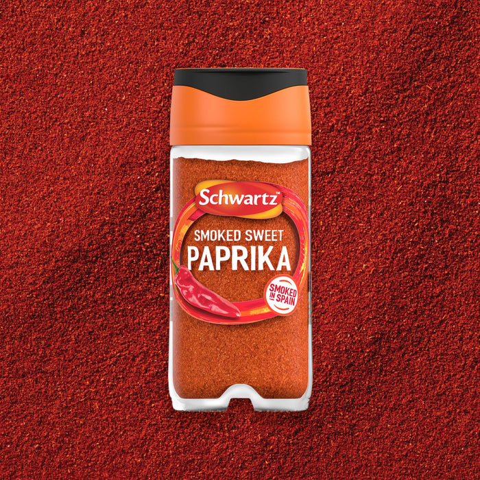 A clear jar of Schwartz Smoked Sweet Paprika 40G is centered on a background of the same vibrant red spice.