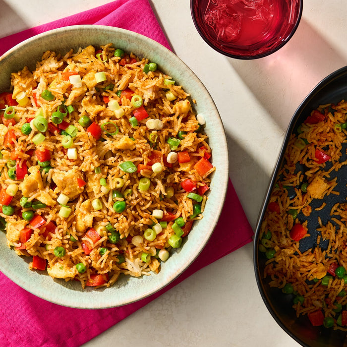 A vibrant bowl of fried rice seasoned with Schwartz Af Chinese Cs Sea and mixed with colorful peas, red peppers, and scrambled eggs.