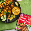 A package of Sa Rt Chicken Satay X12 from Schwartz is displayed next to a finished dish of chicken satay skewers, peanut dipping sauce, and fresh cucumber and lime.