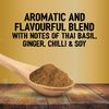 A wooden spoon holds a mound of Jr Thai Sweet Chil Seas X6 seasoning over a rustic wooden table against a gold background with text describing the aromatic blend of Thai basil, ginger, chilli, and soy.