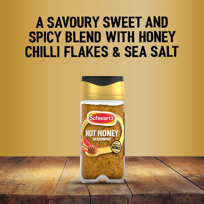 A bottle of Schwartz Jr Hot Honey Seas X6 stands on a rustic wooden surface against a golden background featuring text describing the savoury sweet and spicy blend with honey chilli flakes and sea salt.