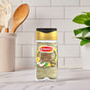 A bottle of Schwartz Jr Garlic Butter Seas X6 stands on a marble countertop in a bright kitchen setting with wooden utensils in the background.
