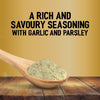 A wooden spoon holds a heap of Jr Garlic Butter Seas X6 over a rustic wooden table against a gold background with text describing it as a rich and savoury seasoning with garlic and parsley.