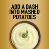 A top-down view of a bowl of creamy mashed potatoes garnished with a sprig of dill suggests that you add a dash of Jr Garlic Butter Seas X6 for extra flavor.