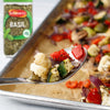 A spoonful of roasted cauliflower, zucchini, and red peppers seasoned with Schwartz Basil 10G is held over a baking tray of colorful vegetables.