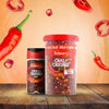 A small jar of Schwartz Crushed Chillies 29G and a larger value tub are displayed on a rustic wooden table, with fresh and sliced red chillies in the background to showcase the main ingredient.