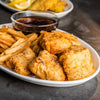 A delicious-looking plate of fish and chips is seasoned with a sprinkle of Schwartz Ground Black Pepper, 33G, and served with a dark dipping sauce.