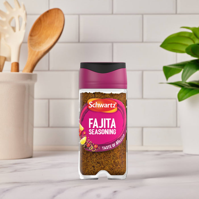 A bottle of Schwartz Fajita Seasoning 46G stands on a marble countertop in a bright kitchen setting.
