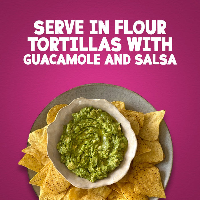 A serving suggestion for Schwartz Fajita Seasoning 46G featuring a bowl of fresh guacamole surrounded by crunchy tortilla chips against a vibrant pink background with text instructions to serve in flour tortillas with guacamole and salsa.