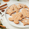 A white plate filled with festive gingerbread men and star shaped cookies that were baked using Schwartz Ground Ginger 26G Jar and decorated with white icing.