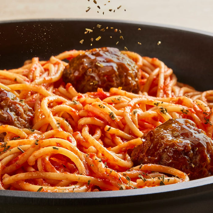 A delicious-looking bowl of spaghetti and meatballs is being finished with a sprinkle of Schwartz Parsley, 3G.