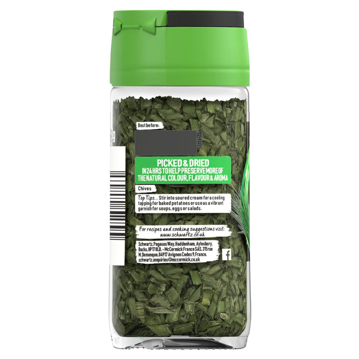 A clear glass jar of Schwartz Chives, 1G shows the dried green herbs through the bottle and features a label with serving suggestions and brand contact information.