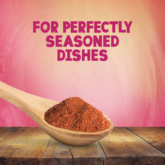 A wooden spoon overflowing with Schwartz Salt, Paprika & Pepper Season All Seasoning 70G rests on a rustic wooden table against a pink textured background with the text FOR PERFECTLY SEASONED DISHES.