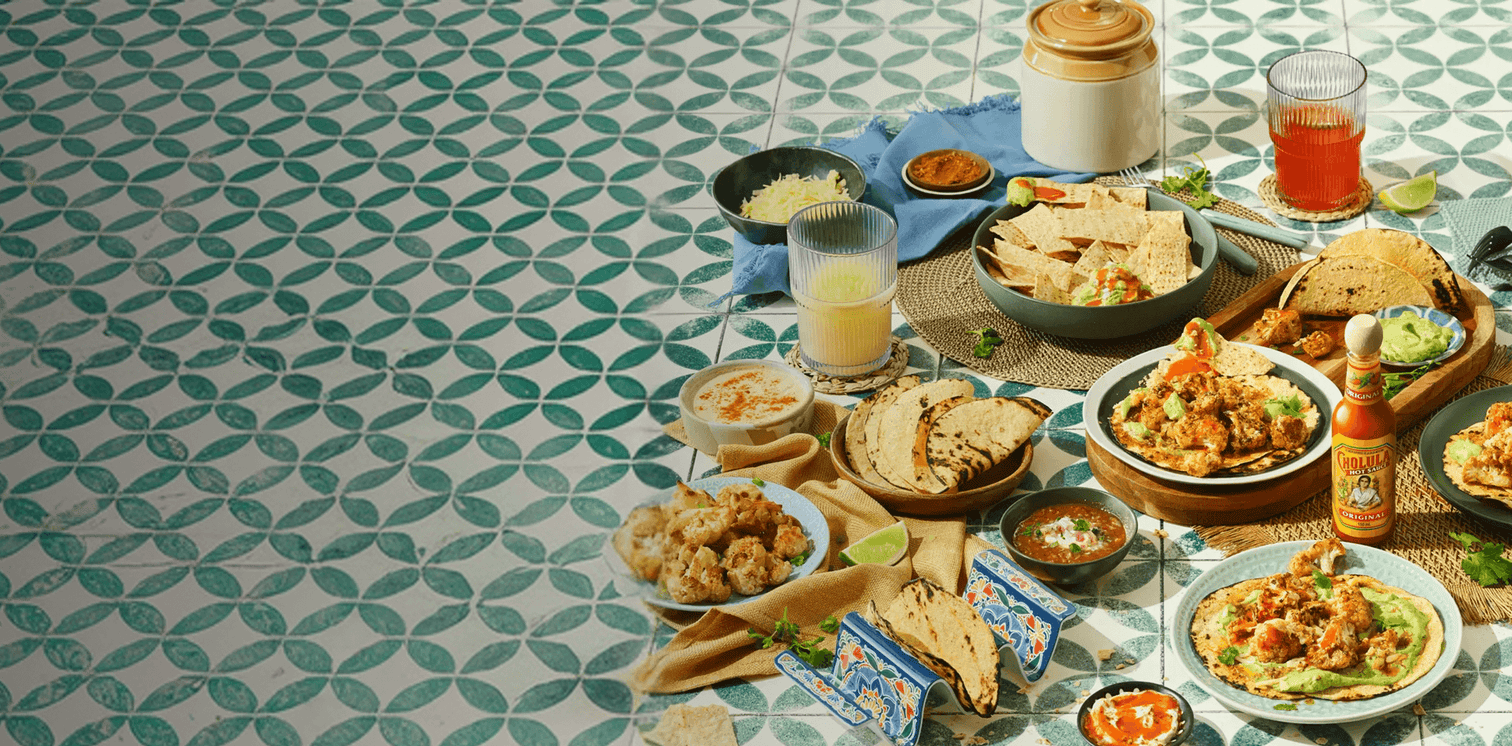 Diverse Mexican food and drinks on a patterned tablecloth