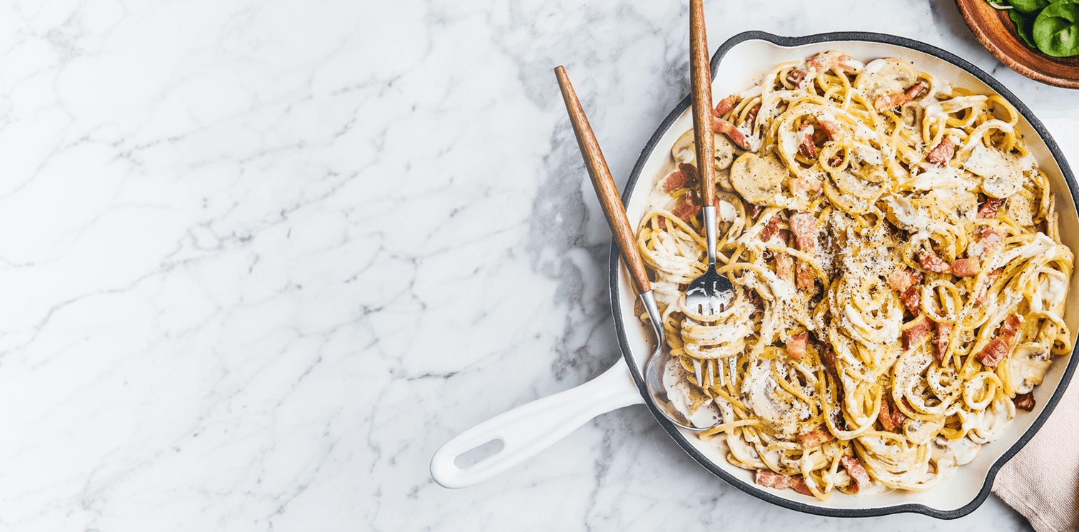 Pasta dish in a white pan on a marble countertop