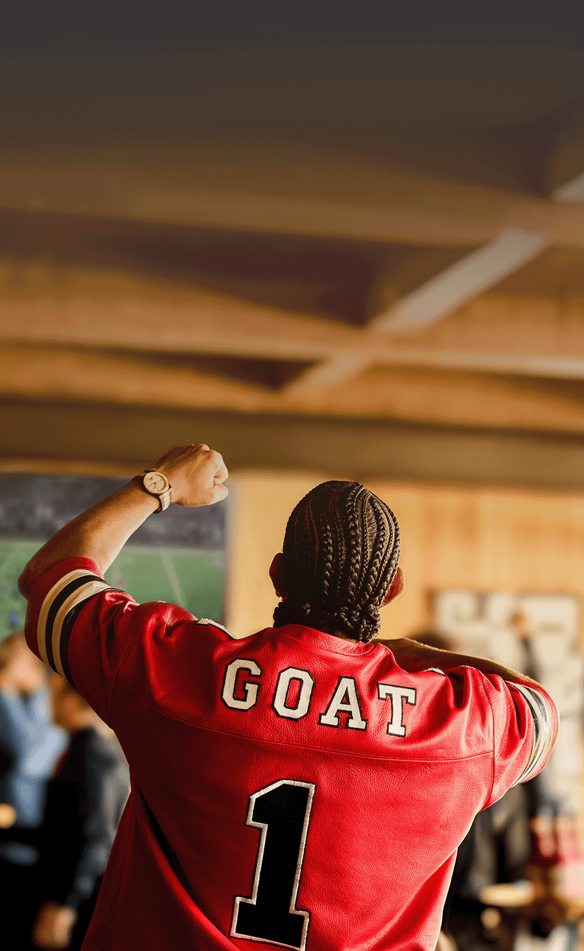 Person wearing a red sports jersey with 'GOAT' and number '1' in a stadium setting