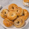 A variety of fresh bagels, including sesame, poppy seed, and everything, are piled on a plate, ready to be enjoyed as part of a delicious Barrel breakfast.