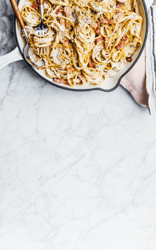 Pasta dish in a skillet on a marble surface