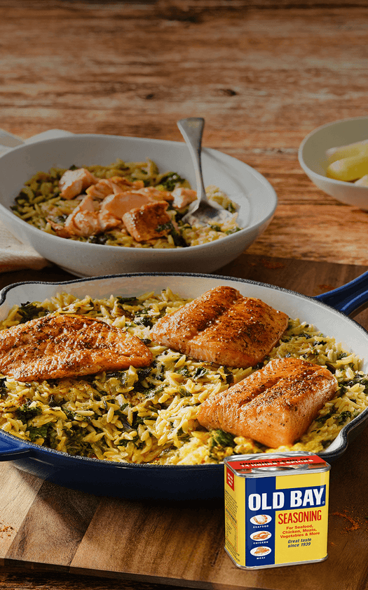 Salmon dish with rice and greens on a wooden table, featuring Old Bay seasoning.