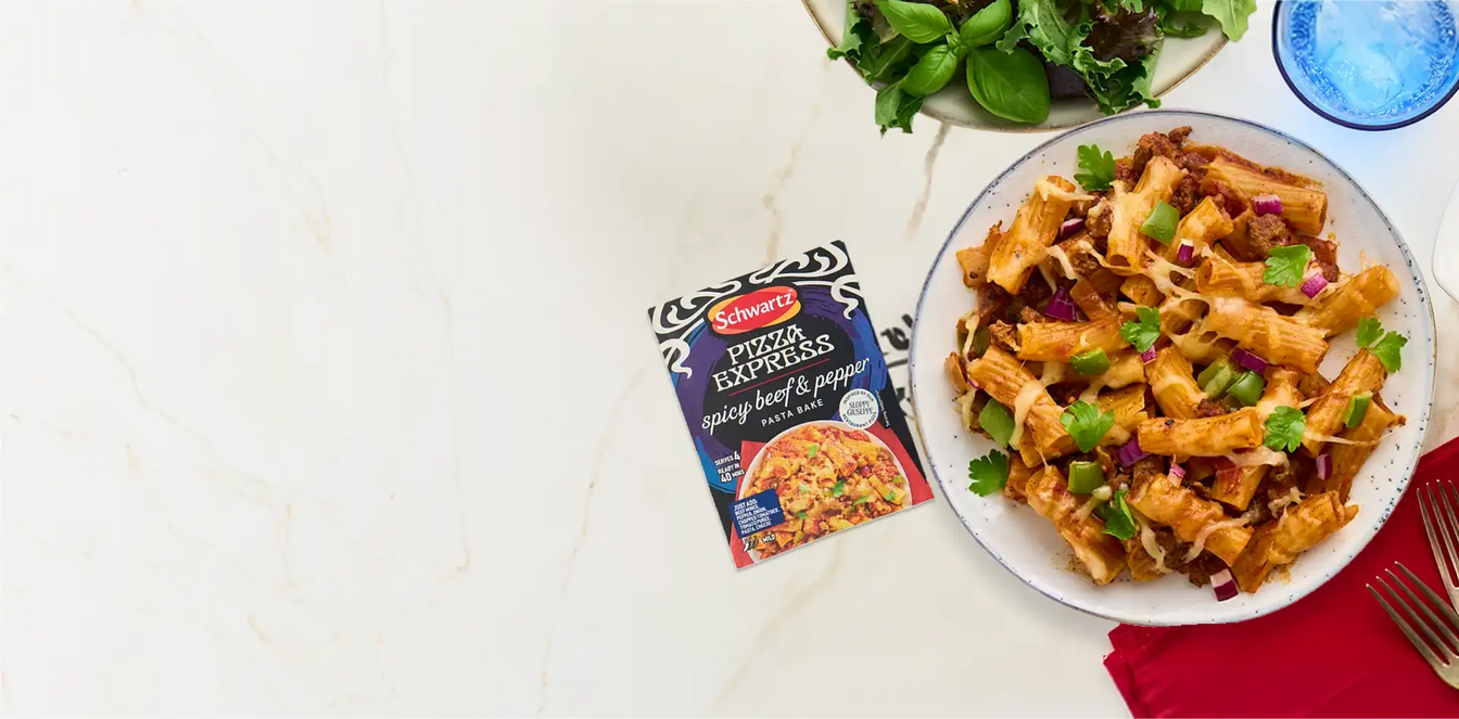 Pasta dish with a package of Schwartz Pizza Express on a table
