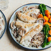 A delicious-looking meal of chicken tenders in a creamy mushroom sauce is served over wild rice with a side of broccolini and carrots.