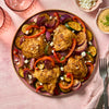 A platter of roasted chicken thighs and vegetables, seasoned with a Barrel spice blend, is garnished with feta cheese and served with a creamy dipping sauce.