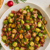 A festive holiday side dish of roasted Brussels sprouts and bacon, seasoned with Barrel, is served in a decorative bowl with a gold spoon.