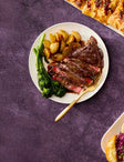 steak and potatoes along with other dishes on a purple table