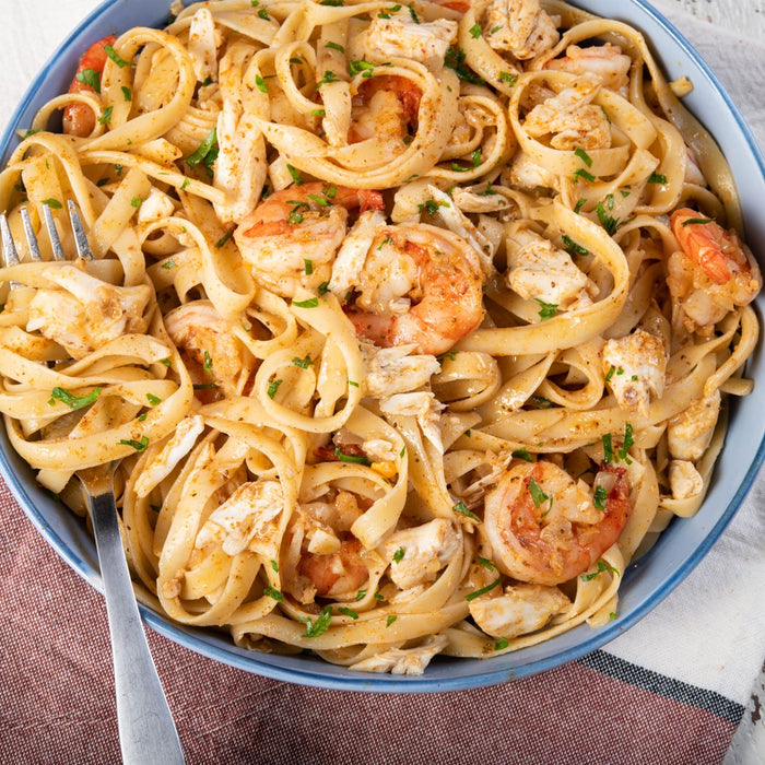 A delicious bowl of fettuccine with shrimp and crab is shown, a perfect recipe to create with a seasoning from a Barrel.