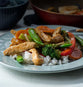 A plate of chicken stir fry with rice, broccoli, carrots, peppers, and snow peas.